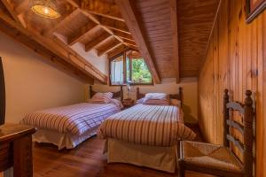 two beds in a room with wooden walls at Casavieja Rural in Abiada