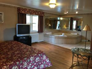 ein Hotelzimmer mit einer Badewanne, einem Bett und einem TV in der Unterkunft Colonie Inn and Suites in Latham