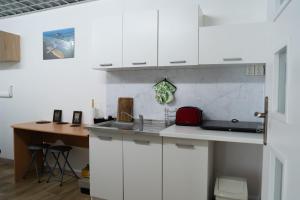 a kitchen with white cabinets and a sink and a desk at Penzión Oliver Humenné in Humenné