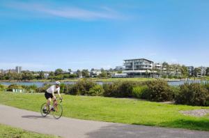 a man riding a bike down a sidewalk at Luxe Riverside Oasis 3BR for 6 Guests Home Near Flemington Racecourse 16 min to CBD 20 min to Airport 2 mins walk to Public Transport to go to Train Station and Highpoint Shopping Centre in Melbourne
