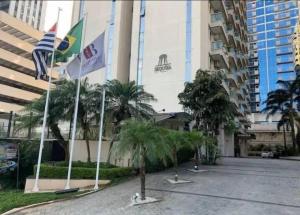 a building with flags and palm trees in front of it at Flat Sequoia Residence in Aldeia