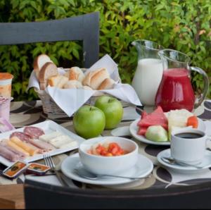 a table topped with plates and bowls of bread and fruit at Flat Sequoia Residence in Aldeia