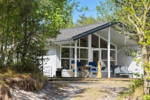 een wit huisje met een veranda en een tafel en stoelen bij 1502-Aakirkeby-Malurtvej-7 in Vester Sømarken