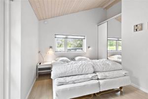 ein weißes Schlafzimmer mit einem Bett und einem Spiegel in der Unterkunft 1435 Aakirkeby - Ædjavejen 10 in Vester Sømarken