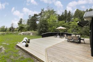 eine Holzterrasse mit Stühlen, Tischen und einem Sonnenschirm in der Unterkunft 1435 Aakirkeby - Ædjavejen 10 in Vester Sømarken