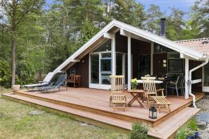 ein Haus mit einer Holzterrasse mit Stühlen und einem Tisch in der Unterkunft 2681 Nexø - Munkegårdsskoven 26 in Neksø