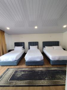 two beds in a room with white walls at Kundasang Komfy Villa with Mount Kinabalu View in Kundasang +15 photos