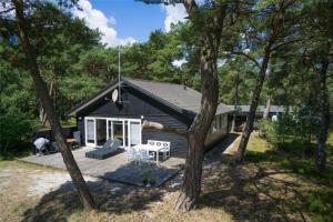 a black house with a porch and a table and chairs at 2531-Nexo-Pilegardsvejen-29 in Neksø