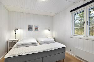 a white bedroom with a bed and two windows at 2531-Nexo-Pilegardsvejen-29 in Neksø