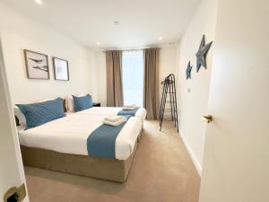a bedroom with a large bed with blue pillows at Wembley Cozy Cloud Waterfront Retreat with Parking near Wembley stadium in London