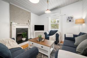 a living room with blue couches and a fireplace at Inchcolm in Leura