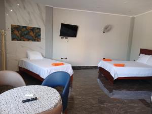 AguaytíaにあるCafé Aguaytiaのベッドが2つと壁にテレビがある部屋