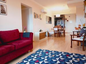 a living room with a red couch and a dining room at 2 suítes - 7 lugares, sua família prox Catedral de Pedra in Canela