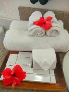 two towels with red flowers on a wooden tray at Asia Grand View Hotel in Coron