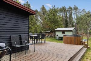 a wooden deck with chairs and a table and a grill at HA374-Saeby-Klitvej-12 in Sæby
