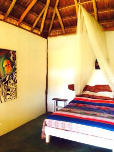 1 dormitorio con 1 cama y una pintura en la pared en Villa Feronia Tulum, en Tulum