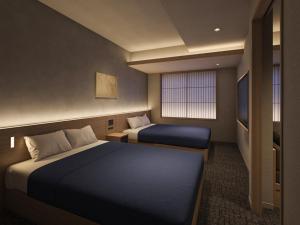 a hotel room with two beds and a television at Minn Kawaramachi Gojo Riverside in Kyoto