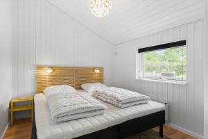 a bedroom with two pillows on a bed with a window at OH551-Hadsund-Ved-Fruerlund-35 in Hadsund