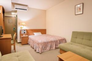 Una habitación de hotel con una cama, un sofá y una silla. en Matsue Universal Hotel, en Matsue
