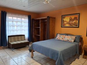 Un dormitorio con una cama y una silla y una ventana. en Apartamentos Quepos Malichita Studio, en Quepos