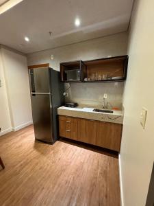 une cuisine avec un réfrigérateur en acier inoxydable et des armoires en bois dans l'établissement Ap Barretos Park - O quarto mais luxuoso do hotel, à Barretos
