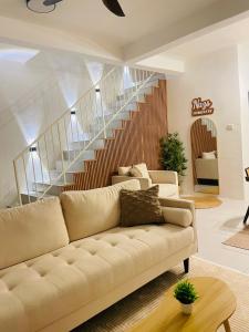 ein Wohnzimmer mit einer Couch und einer Treppe in der Unterkunft NAZS Homestay sungai petani in Sungai Petani