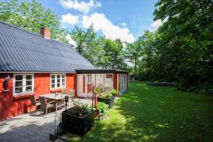 a small red house with a table and chairs in a yard at LF11124-Struer-Vesterkaervej-24 in Struer