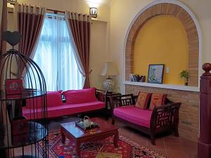 a living room with pink couches and a large window at Mekong Palm House in Can Tho