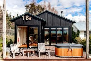 ein schwarzes kleines Haus mit einer Badewanne auf einer Terrasse in der Unterkunft Stargazers Luxury Retreat in Lake Tekapo