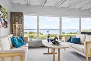a living room with white furniture and large windows at LF14127-Roslev-Kybehuse-127 in Roslev