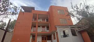 an orange building with a white at Casa Tejedora in Chincheros