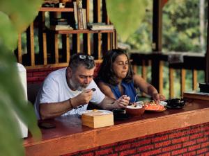 a man and a woman sitting at a table eating food at The stones villa in Pawenang