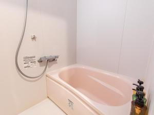a bath tub in a bathroom with a shower at Tabist Business Hotel Kawaramachi in Takamatsu