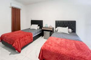 a bedroom with two beds and a red blanket at RedDoorz Syariah at Suatu Villa IKN in Sepaku