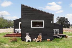 a black house with three dogs sitting outside of it at LF13025-Oster-Assels-Kanalstien-3 in Øster Assels