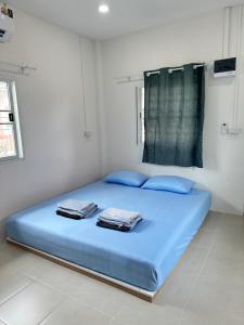a bed with blue sheets and blue pillows in a room at ศาลาลำดวนรีสอร์ต in Ban Sala Lamduan