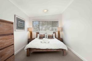 una camera da letto con un letto con lenzuola e cuscini bianchi di Whitewash Cottage by Experience Jervis Bay a Huskisson
