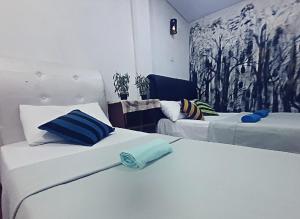 2 weiße Betten in einem Zimmer mit Wandgemälde in der Unterkunft Adams Green View Cottage in Ella