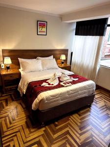 Un dormitorio con una cama grande con dos mesas y dos lámparas. en Hostel Tupac Yupanqui House, en Cusco