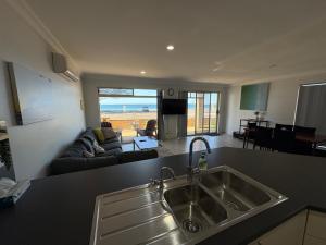 a kitchen with a sink and a living room at Tumby Bay Hotel Seafront Apartments in Tumby Bay +10 photos