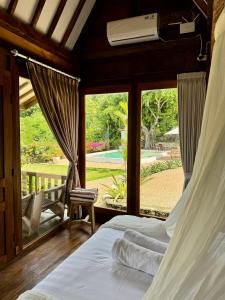 a bedroom with a bed and a large window at 5BR, Ocean View, Private Pool, Villas Roc-Azur in Sampalan