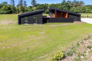 a black house on a hill with a green field at LF12002-Spottrup-Molleparken-17 in Spottrup
