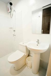 a white bathroom with a toilet and a sink at MGM Tourist Inn in Tagbilaran City