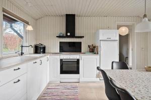 a kitchen with white cabinets and a table with chairs at LF11129-Struer-Tvaervej-29 in Struer +17 photos