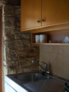 - une cuisine avec un évier et un mur en pierre dans l'établissement Eleni's Cottage, à Apsiou