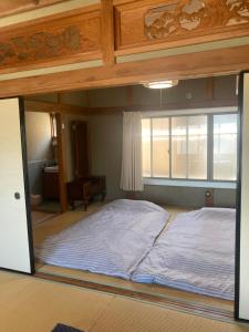 a large bed in a room with a window at お宿とごはん百々 in Tanabe