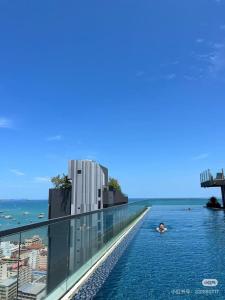 a person swimming in a swimming pool on the roof of a building at The Base Pattaya Seaview Condo in Pattaya