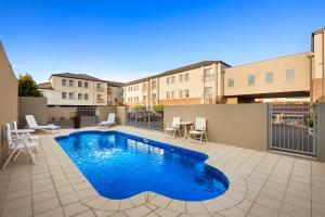 a swimming pool on a patio with tables and chairs at Quest Moonee Valley in Melbourne