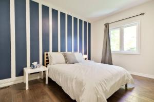 une chambre avec des murs rayés bleus et blancs et un lit dans l'établissement Spacious 4Bdrm Home | Patio, BBQ, Walk to Lake, à Fenelon Falls