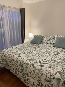 a bedroom with a bed with a green and white comforter at Lindas y acogedoras cabañas en puerto varas. in Puerto Chico
